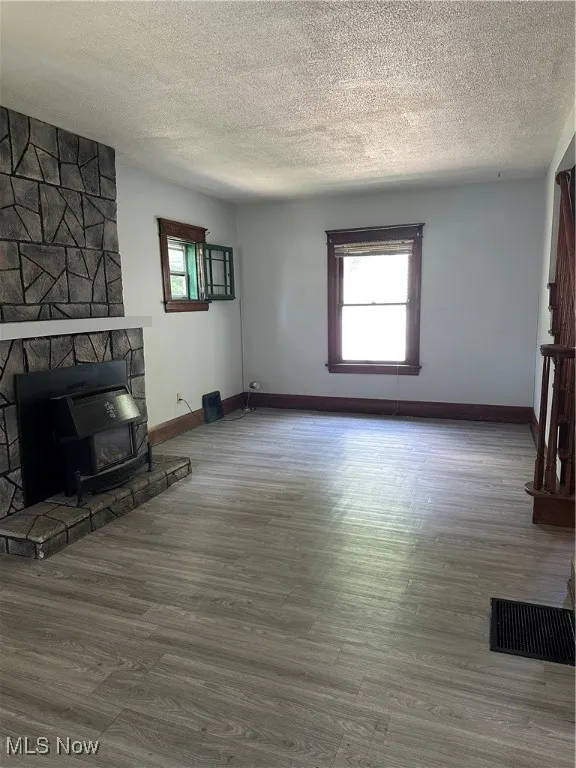 Unfurnished living room featuring plenty of natural light, a textured ceiling, and wood finished floors