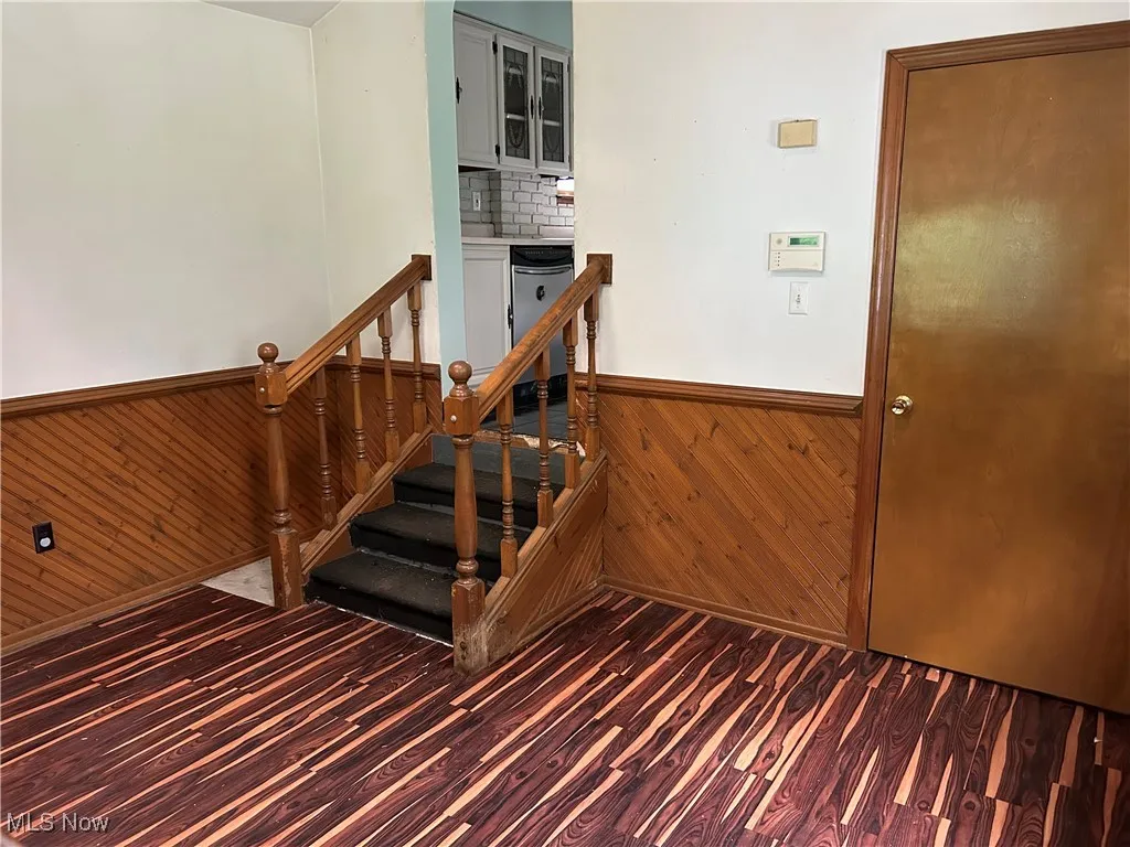 Stairs featuring wood finished floors, wood walls, and a wainscoted wall