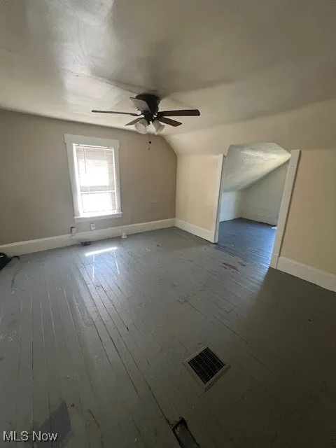 Additional living space with vaulted ceiling, wood-type flooring, and a ceiling fan