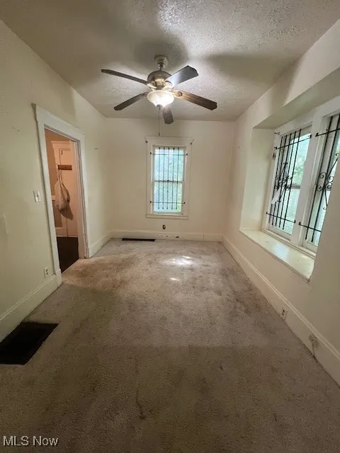 Spare room featuring carpet flooring, a textured ceiling, and ceiling fan