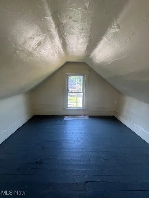 Additional living space with vaulted ceiling and dark wood-type flooring