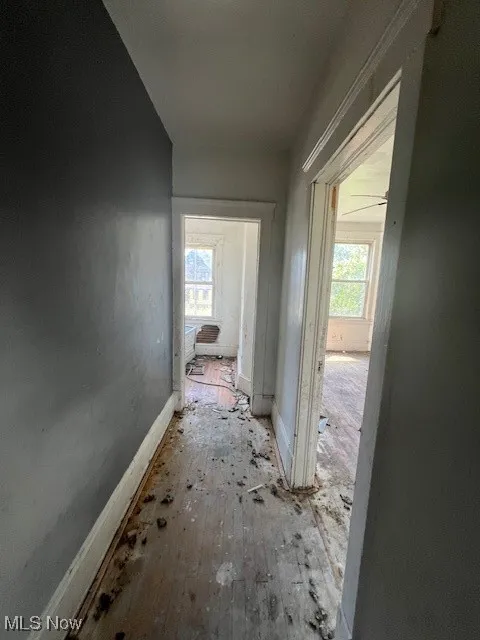 Corridor with healthy amount of natural light and hardwood / wood-style floors
