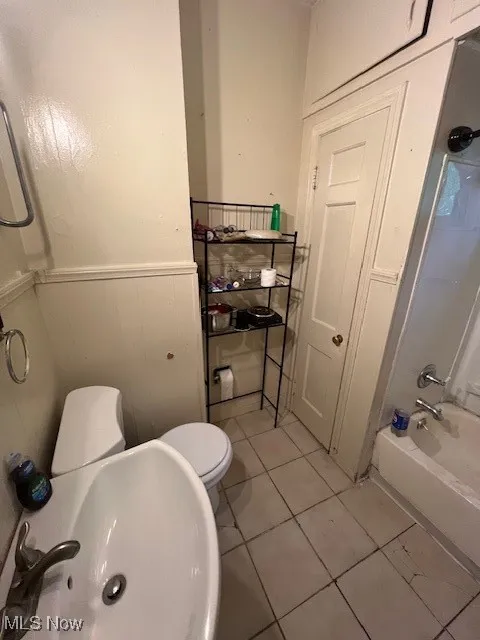 Bathroom featuring a wainscoted wall, tile patterned flooring, and  shower combination