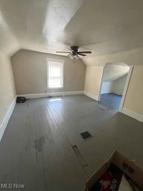 Additional living space featuring lofted ceiling, wood-type flooring, ceiling fan, and arched walkways