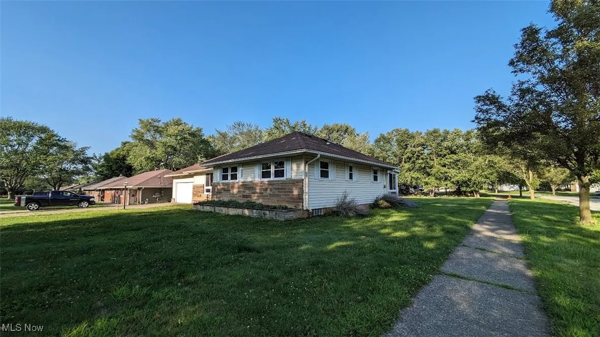 View of property exterior with a yard and an attached garage
