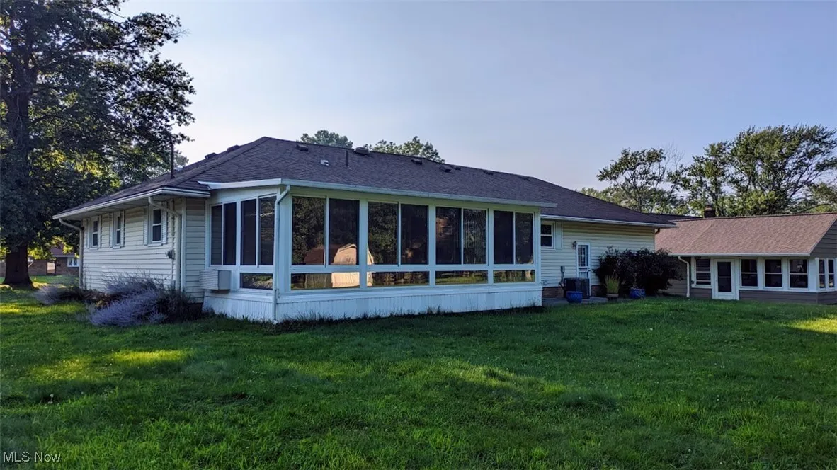 Back of property featuring a sunroom and a lawn
