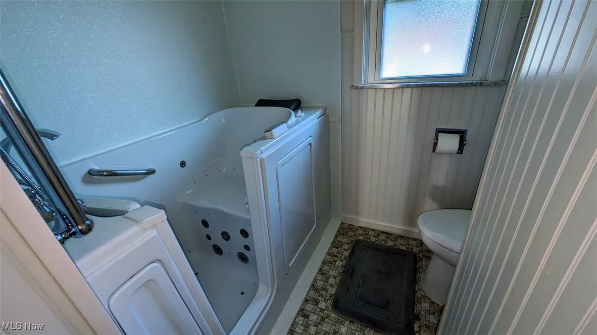 Full bathroom featuring a whirlpool tub and toilet