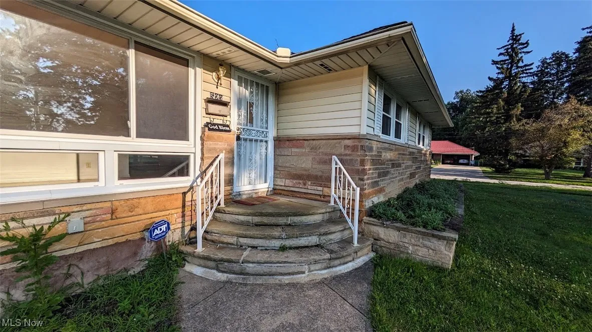 View of exterior entry featuring stone siding and a lawn