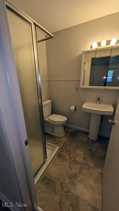 Full bath with a stall shower and a wainscoted wall
