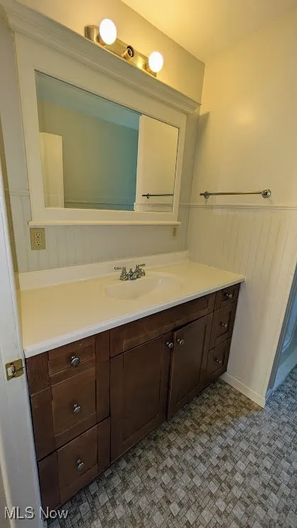 Bathroom with vanity, tile patterned floors, and a wainscoted wall