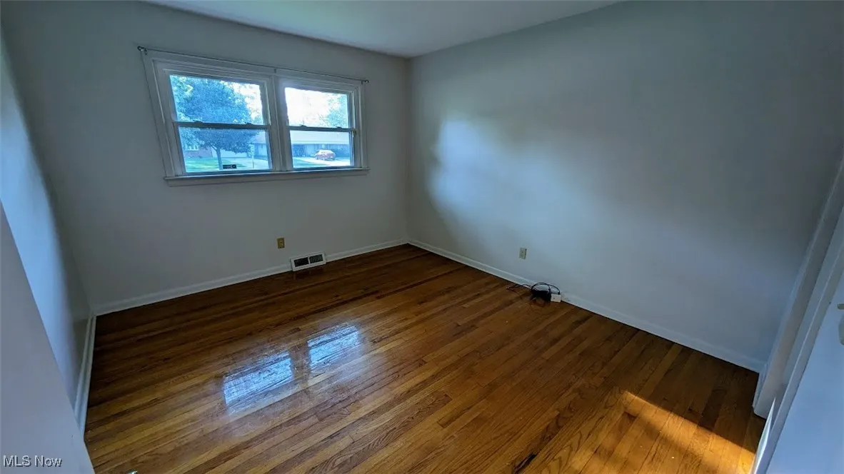 Empty room with dark wood-type flooring and baseboards
