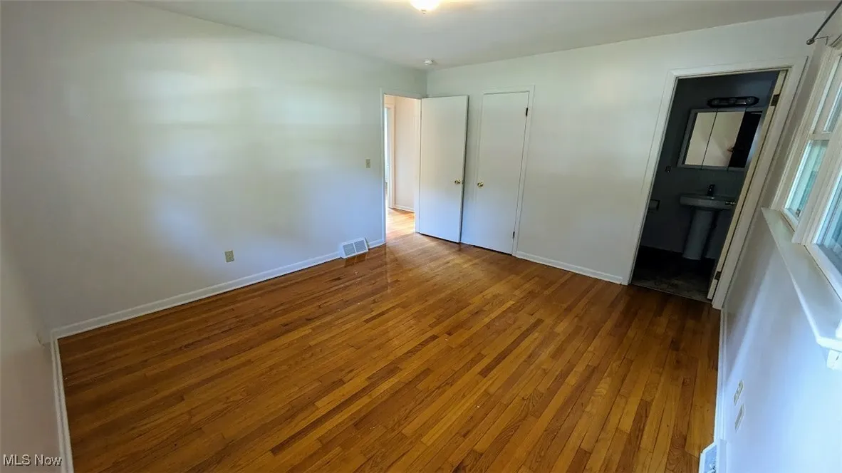 Unfurnished bedroom featuring wood-type flooring and ensuite bath
