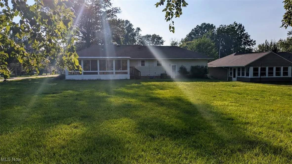 Back of house with a sunroom and a yard