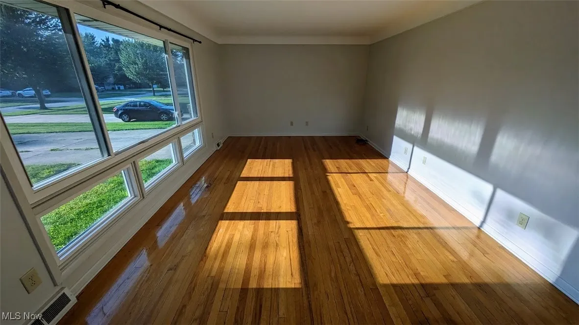 Unfurnished room featuring hardwood / wood-style floors and baseboards