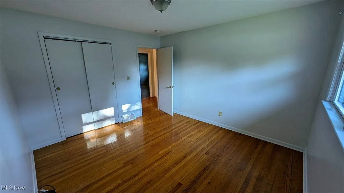 Unfurnished bedroom featuring hardwood / wood-style flooring and a closet