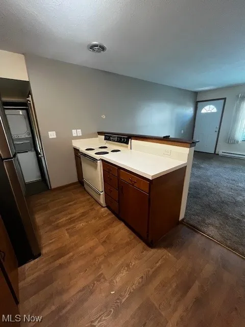 Kitchen featuring a peninsula, white electric range oven, fridge, and dark wood-type flooring
