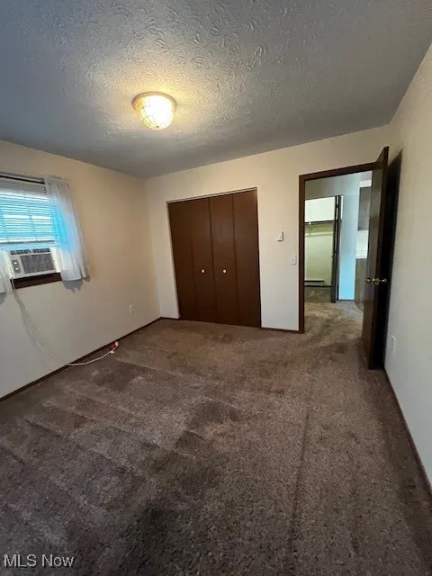 Unfurnished bedroom with carpet flooring, a closet, and a textured ceiling