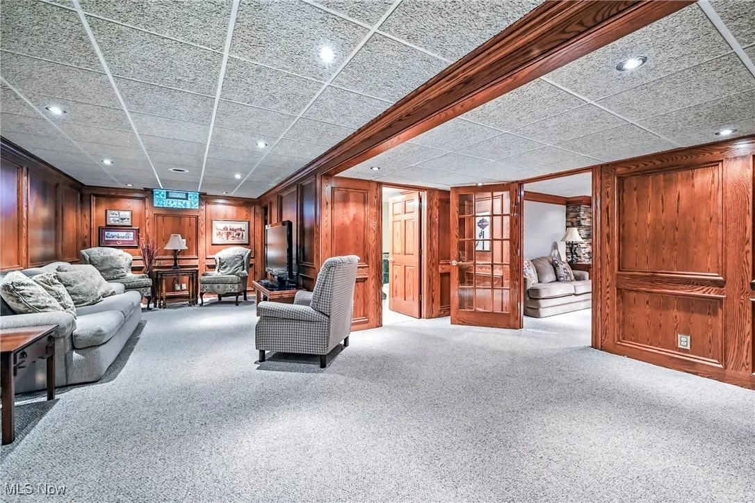 Living area with carpet floors, wood walls, recessed lighting, french doors, and a paneled ceiling
