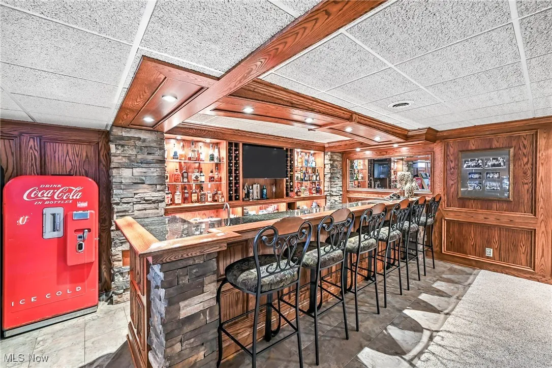 Indoor wet bar with crown molding and wooden walls