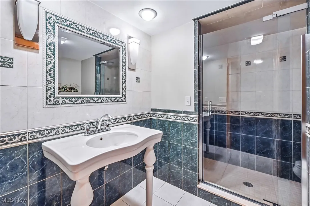 Bathroom with tile walls, a shower stall, and tile patterned floors