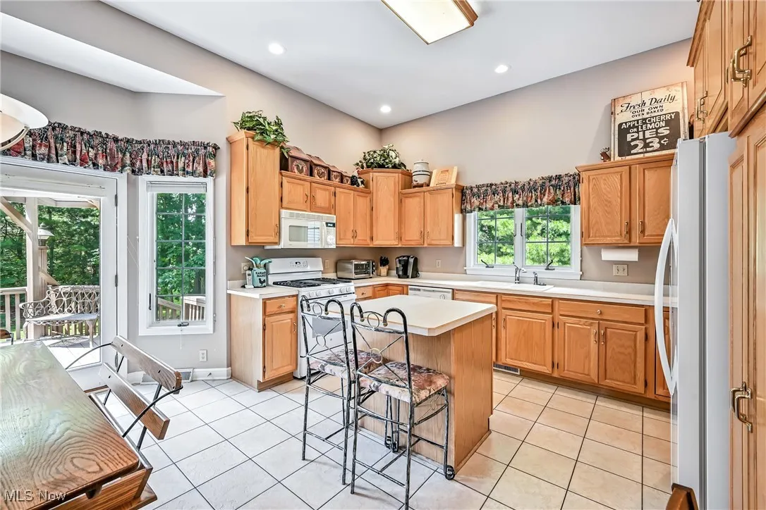 Kitchen featuring light countertops, white appliances, light tile patterned flooring, a center island, and recessed lighting