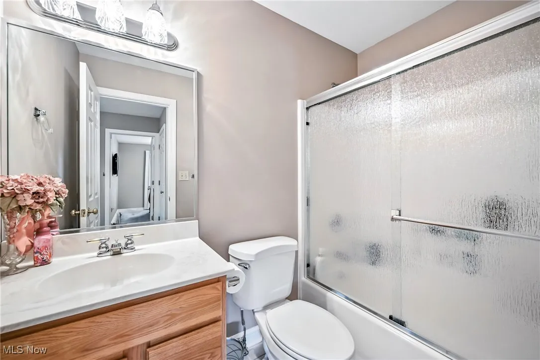Full bath featuring vanity and bath / shower combo with glass door