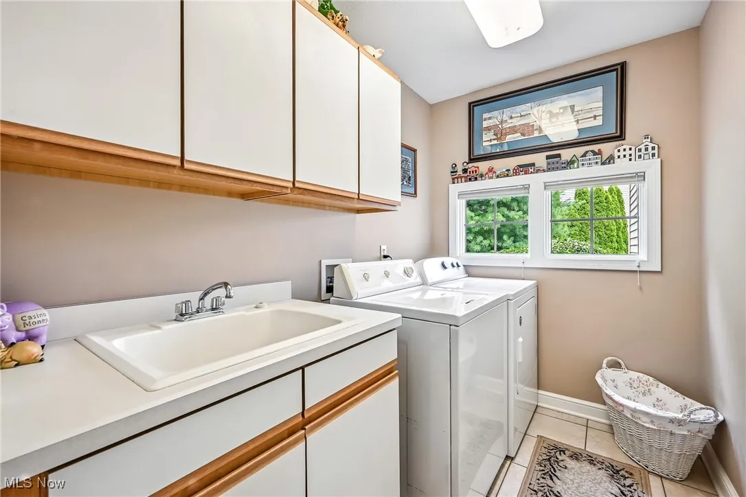 Washroom featuring cabinet space, washing machine and clothes dryer, and light tile patterned flooring