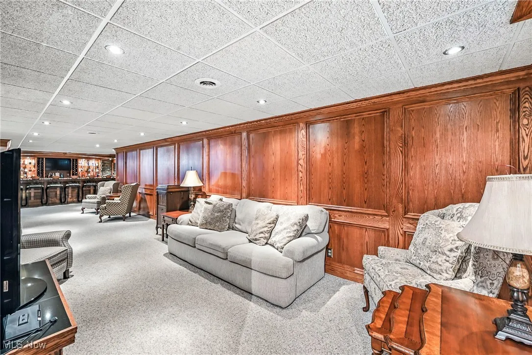 Living area featuring recessed lighting, carpet flooring, and wood walls