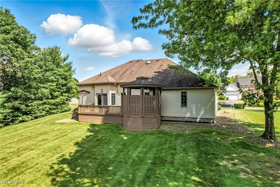 Back of house featuring a gazebo, a lawn, a deck, and roof with shingles