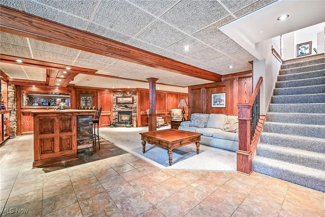 Living room featuring wooden walls, stairway, recessed lighting, and a fireplace