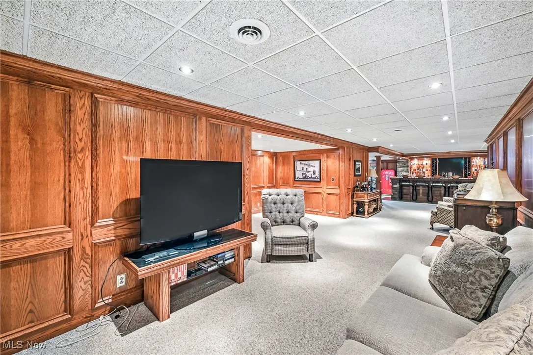 Living area featuring bar area, carpet flooring, recessed lighting, and wooden walls