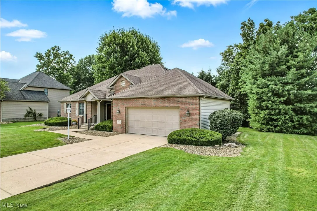 View of front of home with a garage, brick siding, concrete driveway, a front lawn, and a shingled roof