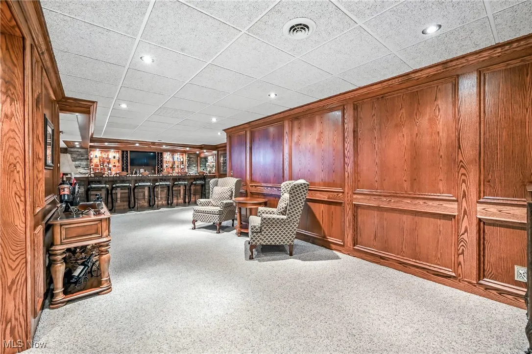 Sitting room with a bar, carpet floors, wood walls, and recessed lighting