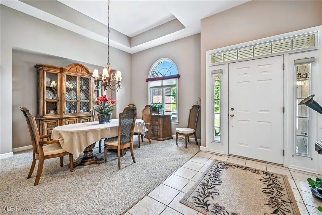 Foyer with a chandelier, light tile patterned floors, a towering ceiling, and a tray ceiling