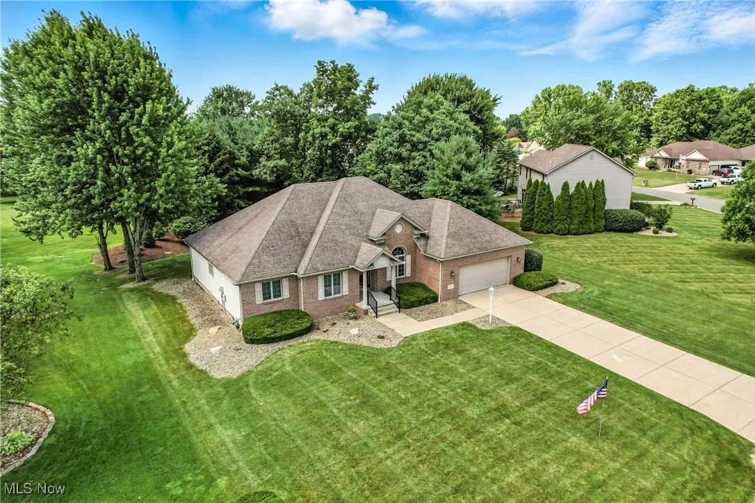 View of front facade with an attached garage, brick siding, driveway, and roof with shingles