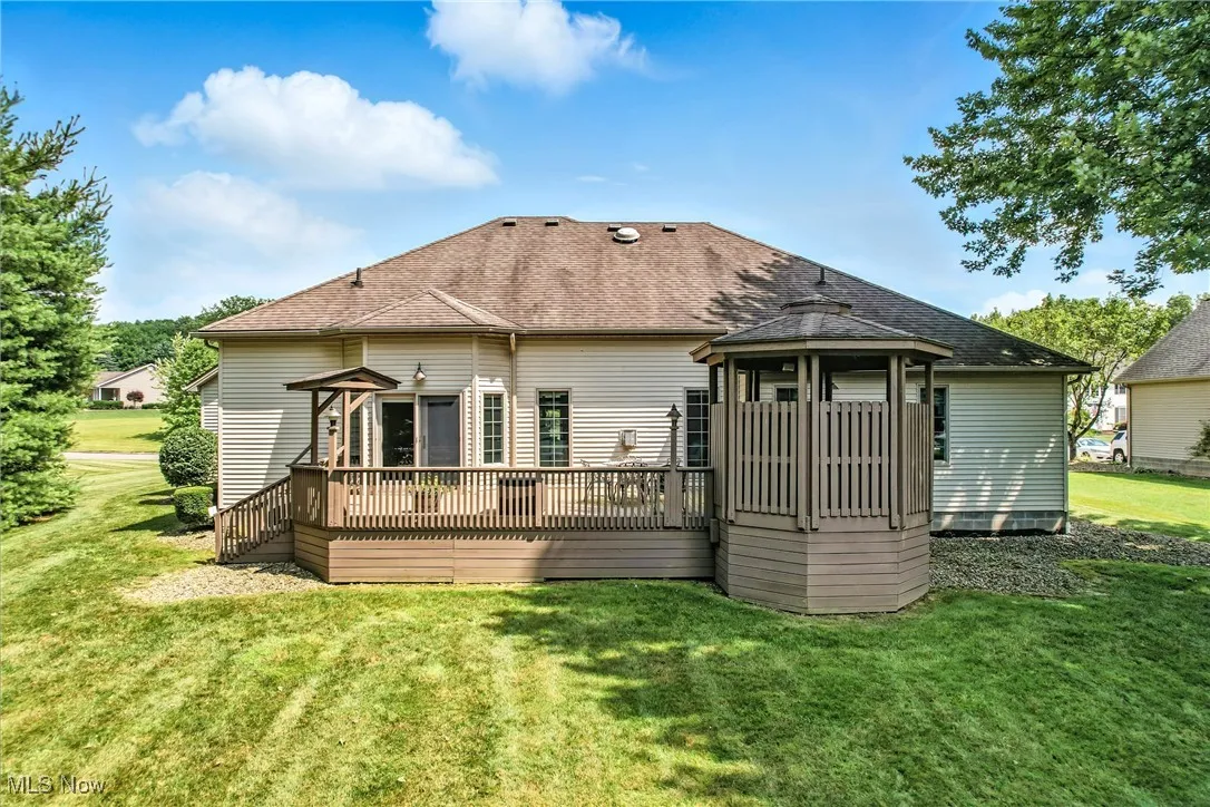 Rear view of house with a gazebo, a shingled roof, a deck, and a yard