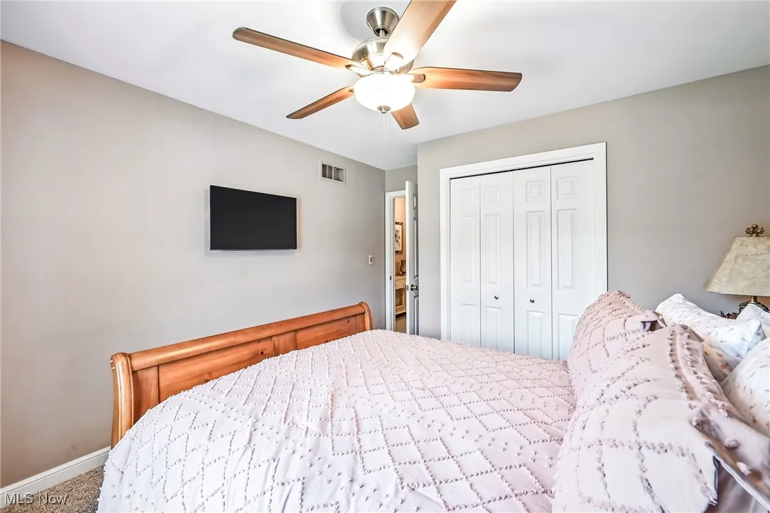 Bedroom with a closet, carpet, and a ceiling fan