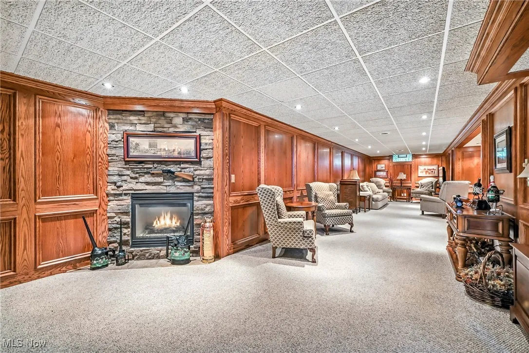Living area featuring recessed lighting, carpet, a fireplace, wood walls, and ornamental molding