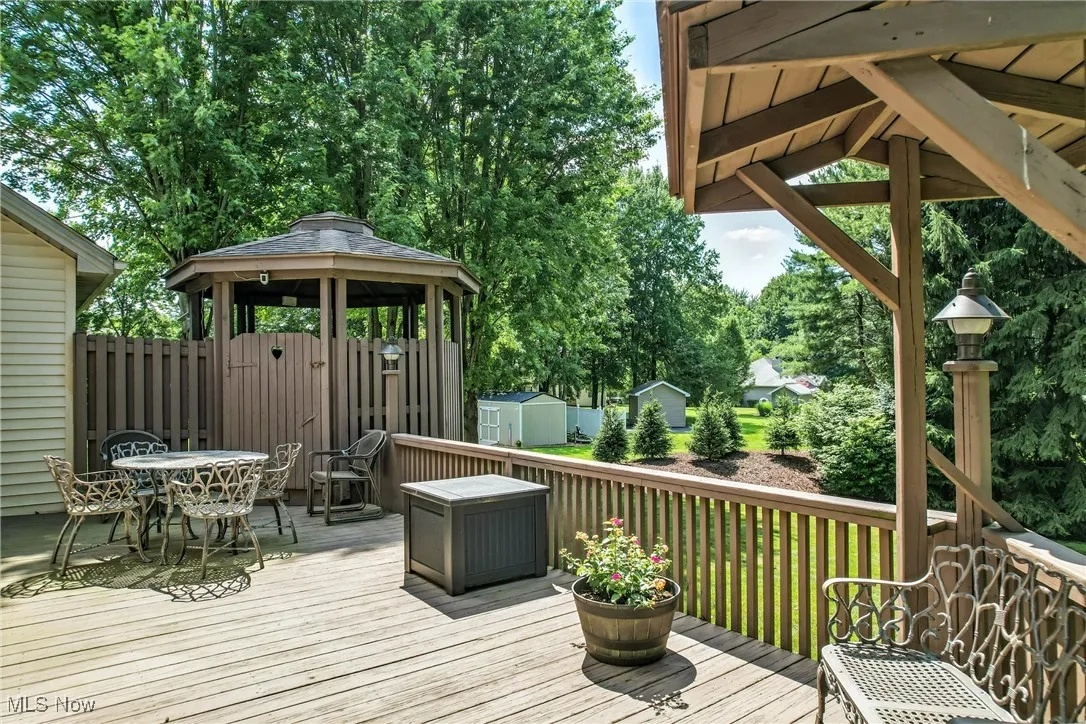 Wooden terrace with a gazebo, a storage unit, and outdoor dining space