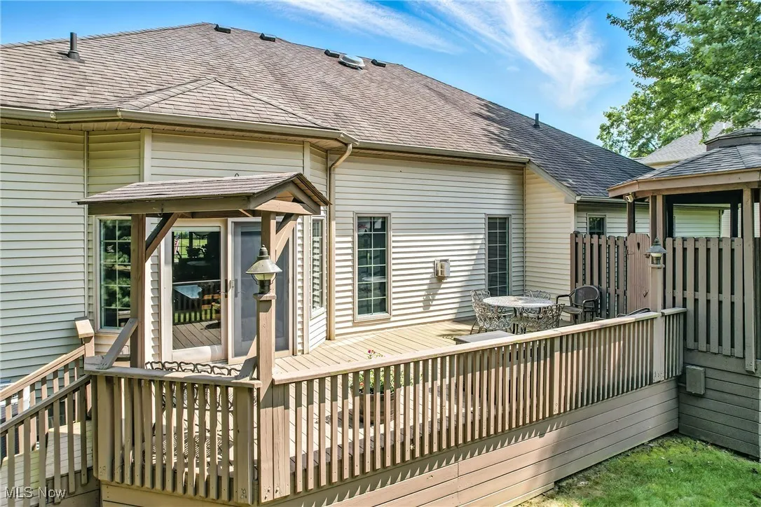 Back of house with roof with shingles, a deck, and outdoor dining space