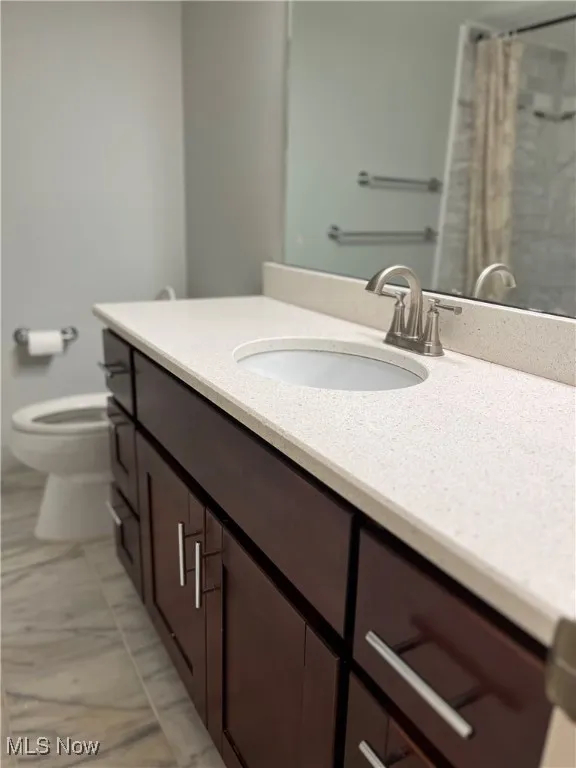 Bathroom featuring vanity, marble finish flooring, and curtained shower