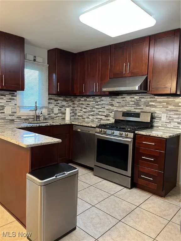 Kitchen with range, light tile patterned floors, and tasteful backsplash