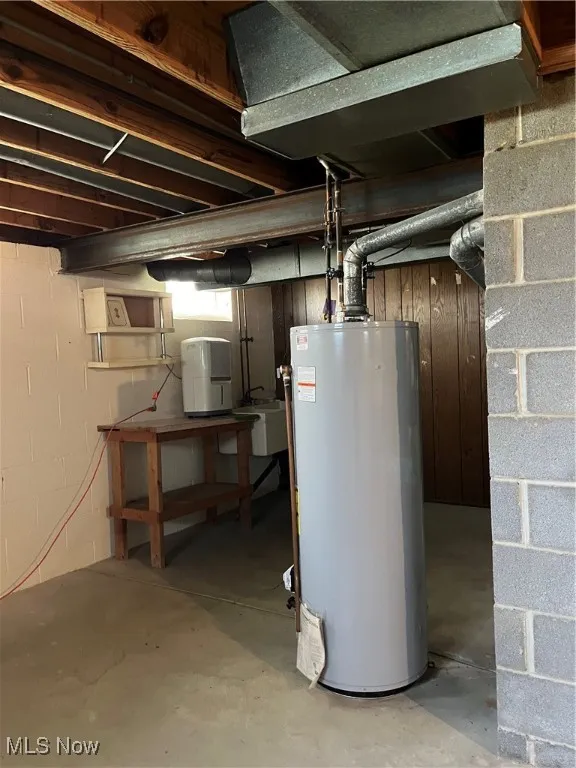 Unfinished basement featuring water heater and a sink