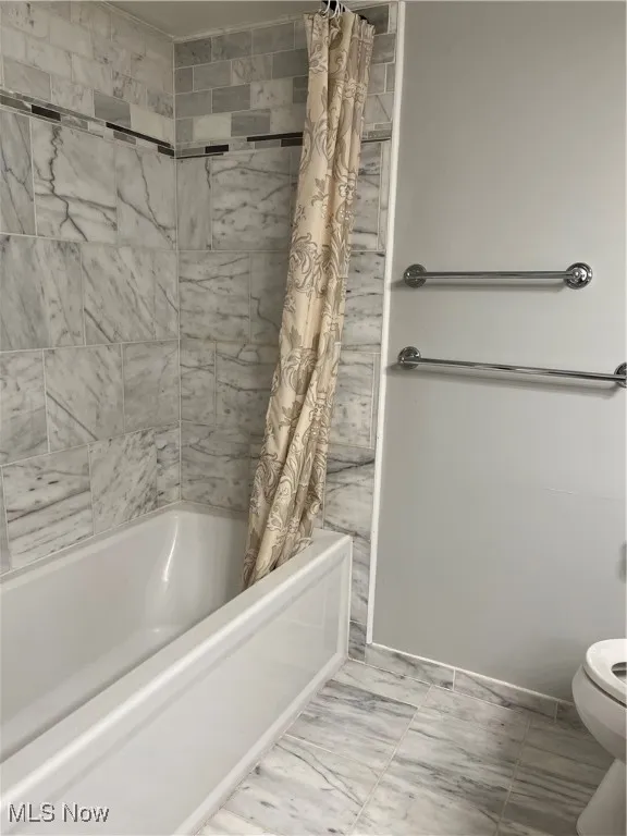 Full bathroom featuring toilet and shower / bath combination with curtain