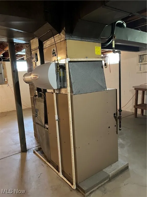 Basement featuring heating unit and concrete block wall