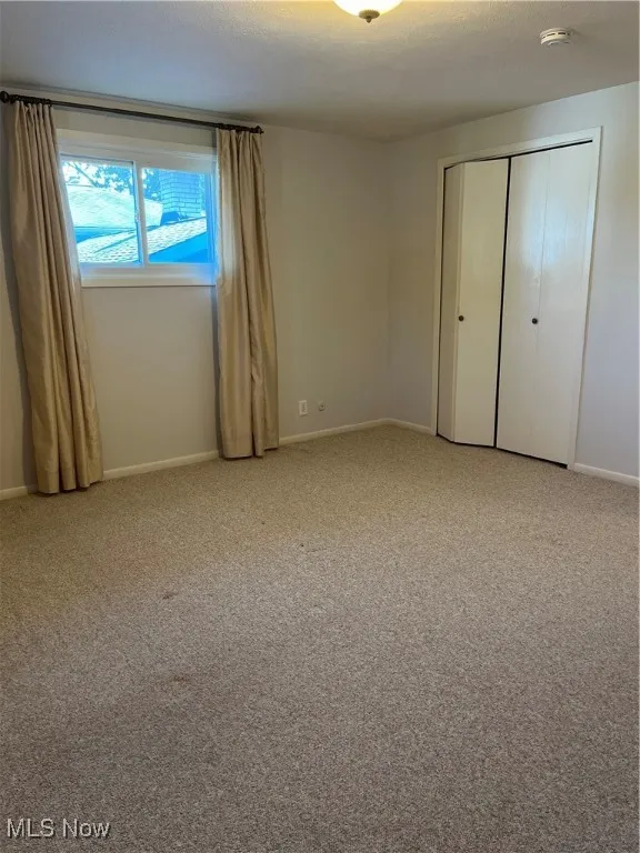 Unfurnished bedroom with light carpet and a closet