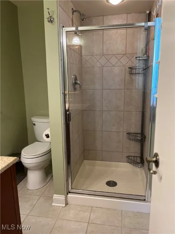 Bathroom with tile patterned flooring, a shower stall, and vanity