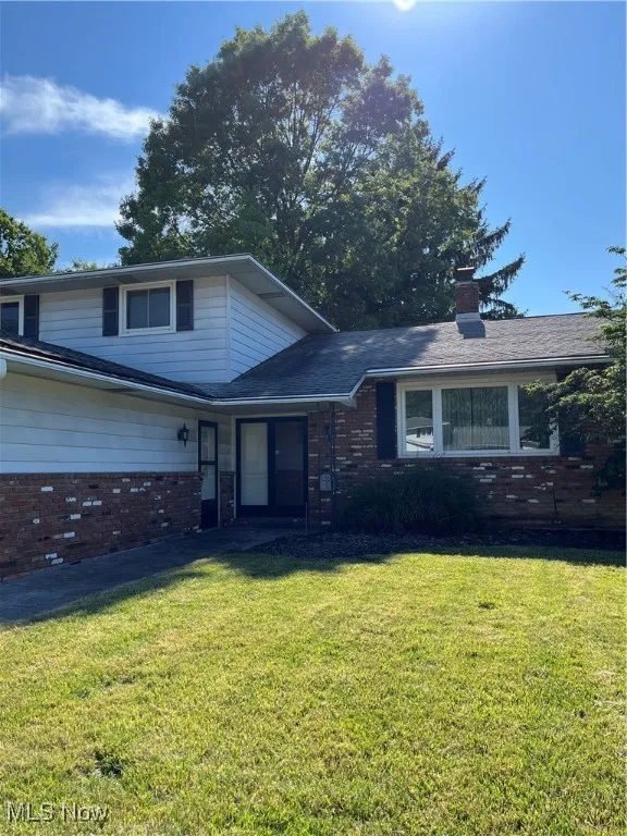 View of front of property featuring brick siding, a front lawn, and a chimney