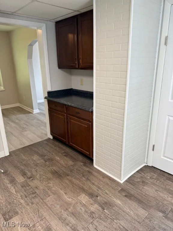 Kitchen featuring luxury vinyl floors, dark countertops, dark brown cabinets, and arched walkways