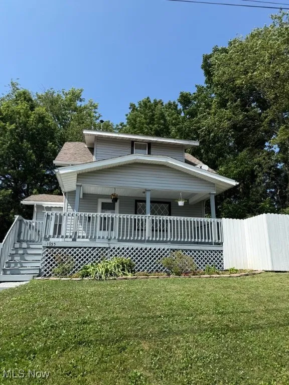 Colonial-style home with a front lawn, covered porch, and a shingled roof